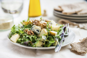 Healthy Salad made from Green Salad Leaves, Rocket Salad, Slices of Fresh Pears, pieces of Blue Cheese, Walnuts and Sesame Seeds. Pieces of Pita Bread nearby